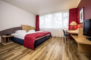 a hotel room with a bed and a desk at ARVENA Messe Hotel in Nürnberg