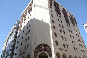 a tall white building with a sign on it at Hayah Grand Hotel Ex Al Jaad Madinah Hotel in Medina