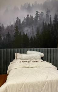 ein Schlafzimmer mit einem Bett und einem Wandbild eines Waldes in der Unterkunft Apple eight 2BR Villa in Batu