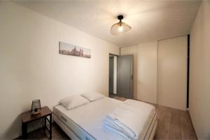 a white bedroom with a bed and a table at Appartement tout équipé climatisé 8 couchages in Marseille