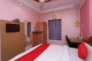 1 dormitorio con 1 cama, escritorio y TV en OYO Hotel Madhur Regency, en Meerut