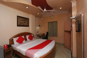 1 dormitorio con 1 cama grande con almohadas rojas en OYO Hotel Madhur Regency, en Meerut