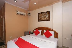 1 dormitorio con 1 cama con almohadas rojas y blancas en OYO Hotel Madhur Regency, en Meerut