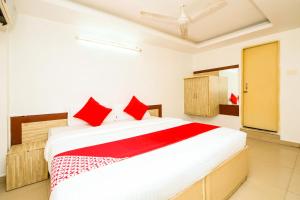 1 dormitorio con 1 cama blanca grande con almohadas rojas en Hotel Cozy Residency, en Jabalpur