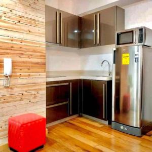una cucina con frigorifero in acciaio inossidabile e sgabello rosso di Modern-Eclectic 1BR- Unit @Milano a Manila