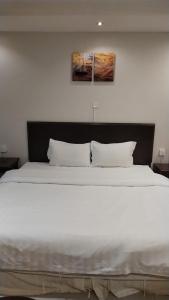 a large white bed with two pillows in a bedroom at Blue Sands Al Bilsan Furnished Units in Dammam