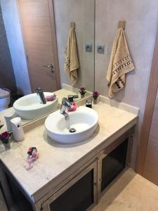 a bathroom with a sink and a mirror at Luxury Apprt 2 ch ,prestigia des nations in Sidi Bouqnadel