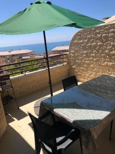 a table with a green umbrella on a balcony at Luxury Apprt 2 ch ,prestigia des nations in Sidi Bouqnadel