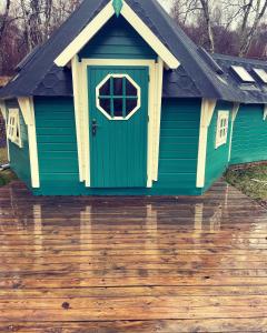 a green dog house on a wooden deck at Lochness Glam Lodges in Inverness