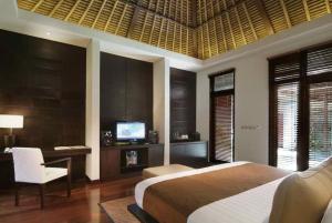 a bedroom with a bed and a desk and a television at Villa Mahapala in Sanur