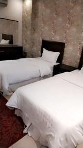 two beds in a hotel room with white sheets at Blue Sands Al Bilsan Furnished Units in Dammam