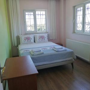 a bedroom with a bed with a table and two windows at Villa Latanya in Dalaman