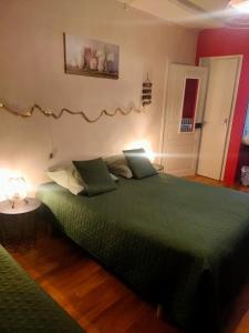Un dormitorio con una cama verde con una manta verde en Cité de caractère médiéval, en Fresnay-sur-Sarthe