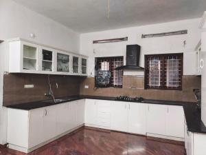 uma cozinha com armários brancos e um balcão preto em White Sands Homestay em Turavūr