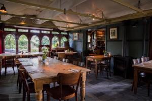 a restaurant with wooden tables and chairs and windows at Uylenburg- Du Midi in Delft