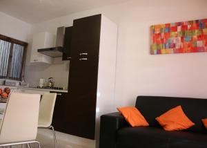 a living room with a black couch and a kitchen at St.Joseph Apartment in Marsaskala