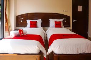two beds in a bedroom with red and white pillows at RedDoorz near Londa Toraja in Madandan