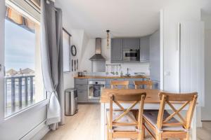 kuchnia z drewnianym stołem i krzesłami obok okna w obiekcie Duplex du Littoral - Vue mer w mieście Villers-sur-Mer