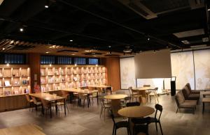 een eetkamer met tafels en stoelen en boekenplanken bij WeBase Kyoto in Kyoto