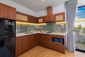 a kitchen with wooden cabinets and a black refrigerator at Lagom Boutique Hotel Da Nang in Da Nang