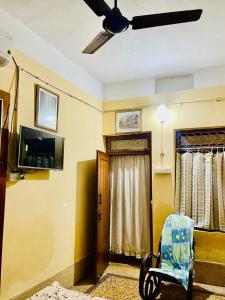um quarto com uma ventoinha de tecto, uma cadeira e uma porta em Divine view - Ac room for 2 pax - Swarna Bhavan em Puri