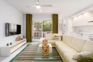 a white living room with a couch and a tv at Marbella playa Residencial con piscina in Marbella