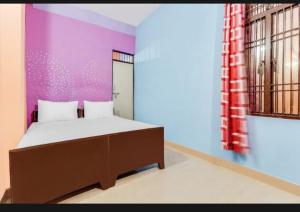 a bedroom with a bed and a purple wall at Hotel Radhe Inn By WB Inn in Agra