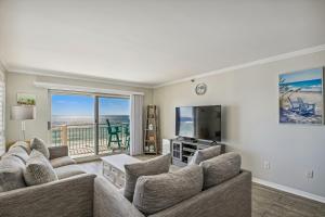 a living room with couches and a television and a balcony at Destin Towers Condo 61 Condo in Destin