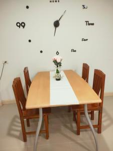 uma mesa de jantar com cadeiras e um relógio na parede em บ้านไอรัก@the neo 