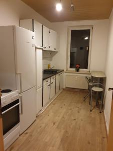 a kitchen with white appliances and a wooden floor at FeWo Nina 3 - Monteurwohnung in Weißenfels