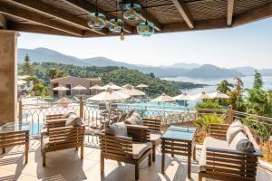 a patio with chairs and tables and a view of the water at Sivota Diamond Spa Resort in Syvota