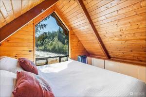 a bedroom with a large window in a wooden cabin at NEW: Steps from White River near Mount Rainier National Park in Greenwater