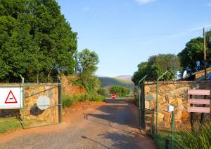 a gate on a road with a stop sign at Highland Run Fly Fishing Estate by Dream Resorts in Lydenburg