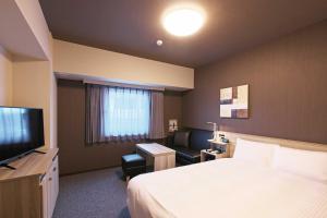 um quarto de hotel com uma cama e uma televisão em Hotel Route Inn Choshi Eki Nishi em Choshi