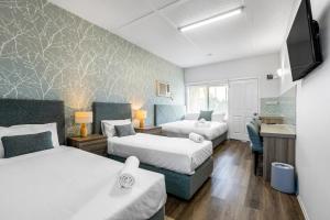Cette chambre comprend deux lits et un bureau. dans l'établissement Rosebud Motel, à Tootgarook