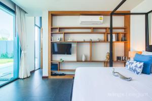 a bedroom with a large bed and a tv at One Bedroom Wings Pool Villa in Bang Tao Beach