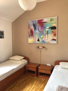 Cette chambre comprend deux lits et un tableau mural. dans l'établissement Apartments Villa More 3 Apartments 4-4-6 Beds, à Bobovišća