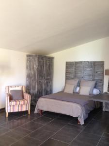 - une chambre avec un grand lit et une chaise dans l'établissement Gite au coeur de la Provence & SPA, à Saint-Cannat