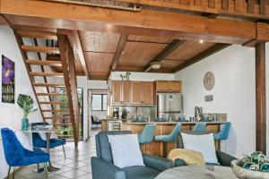 a living room with blue chairs and a kitchen at Oceanside-Spectacular View and Poolside Oasis in Kahana