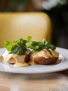a plate with a sandwich with cheese and greens on it at The Madrid EDITION in Madrid
