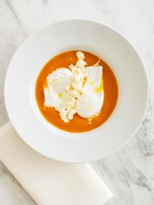 a white plate with a bowl of soup on a table at The Madrid EDITION in Madrid