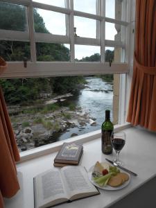 einen Tisch mit einem Buch, ein Glas Wein und ein Fenster in der Unterkunft New Lanark Self Catering Waterhouses in Lanark