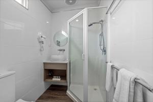 a white bathroom with a shower and a sink at Rosebud Motel in Tootgarook