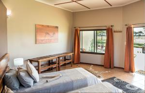 Gobabis的住宿－Africa Awaits Lodge & Safaris，一间卧室配有一张床、一张桌子和一个窗户。