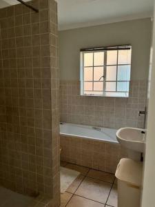 a bathroom with a bath tub and a sink at The Reeds: 2 Bedroom townhouse in Centurion