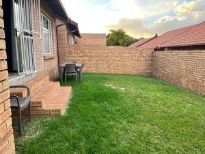 a yard with two chairs and a table and a brick wall at The Reeds: 2 Bedroom townhouse in Centurion