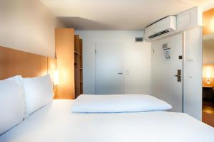 - une chambre avec un lit blanc et un placard dans l'établissement B&B Hotel Düsseldorf-Hbf, à Düsseldorf
