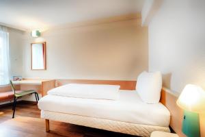 een slaapkamer met een wit bed en een stoel bij B&B Hotel Düsseldorf-Hbf in Düsseldorf