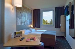 a hotel room with two beds and a desk with a computer at B&B Hotel Düsseldorf-Ratingen in Ratingen