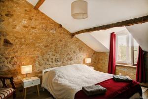una camera da letto con un letto e un muro di mattoni di Maison d'Amis Des Hirondelles a Lempzours Altre 36 foto